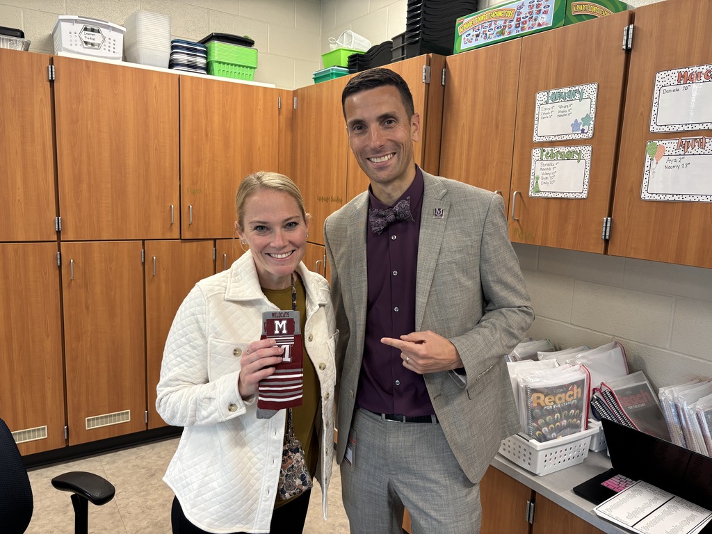 A man in a suit presents a pair of branded socks to a staff member.