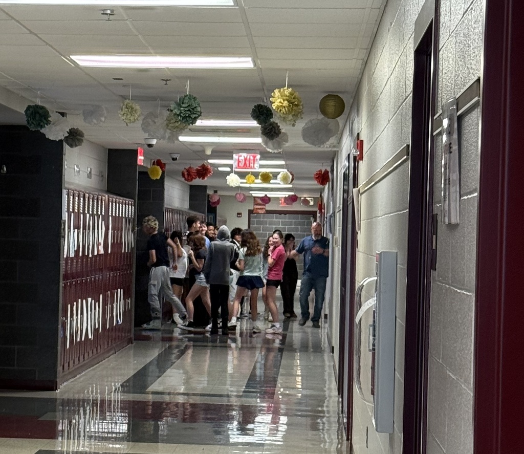 Students run into a school hallway to sing happy birthday to a classmate.