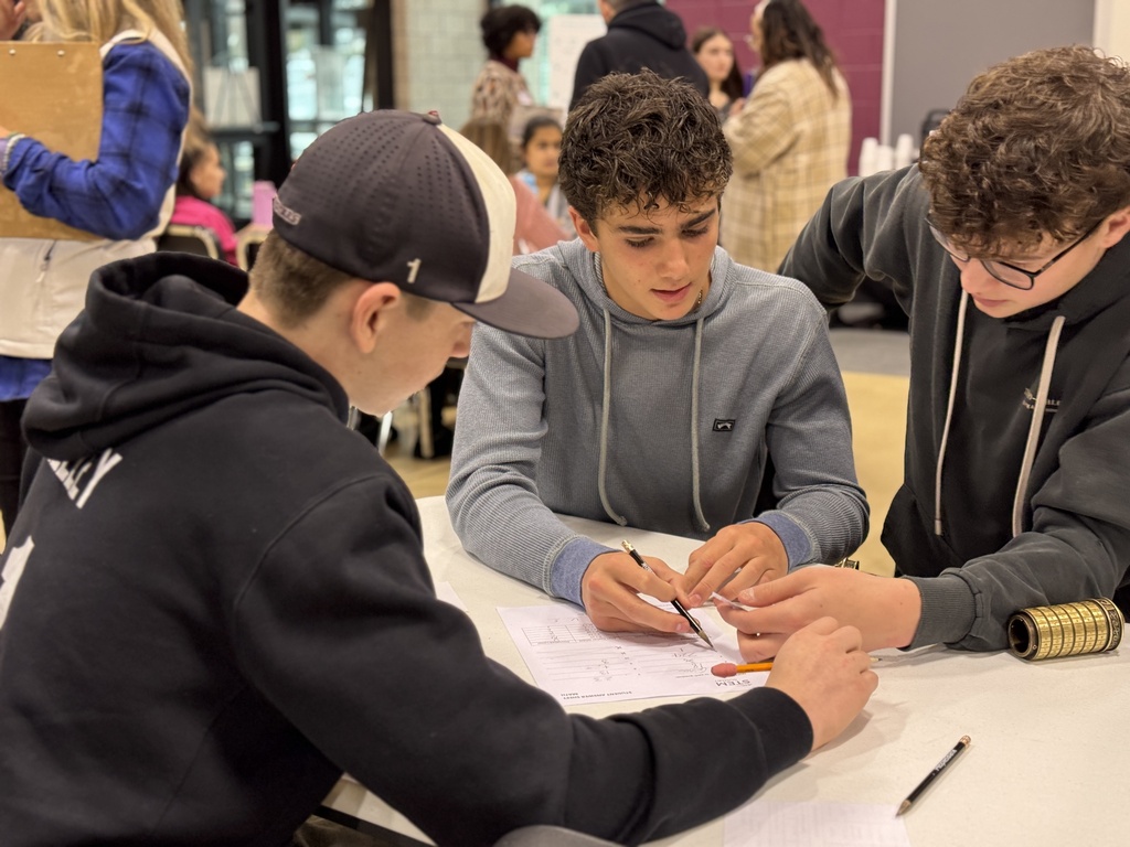 Students work together at a table to solve a science problem.