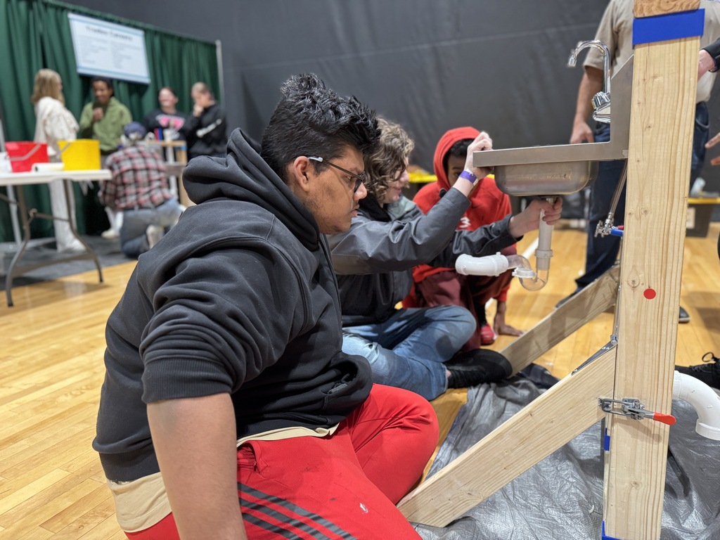 Students work together to fix a plumbing issue as part of a science project.