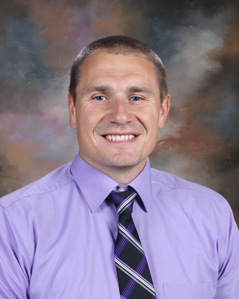 man in purple shirt and black and purple tie in a headshot with a brown and blue background