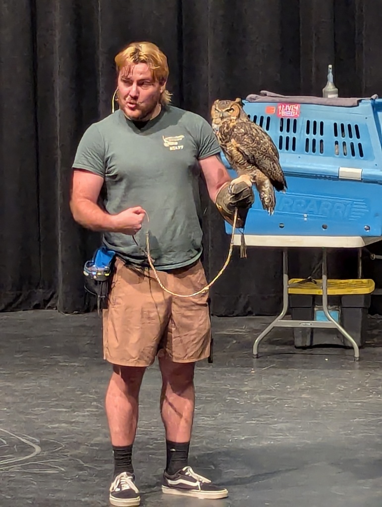 man in green shirt with owl sitting on gloved hand