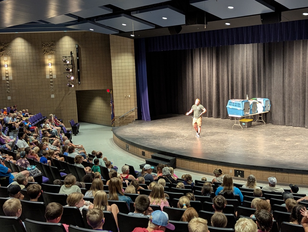 man on stage in a theatre with people sitting in the seats.