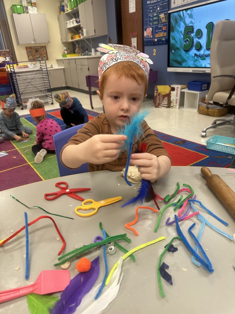 boy with red hair and playing with feathers and pipe cleaners