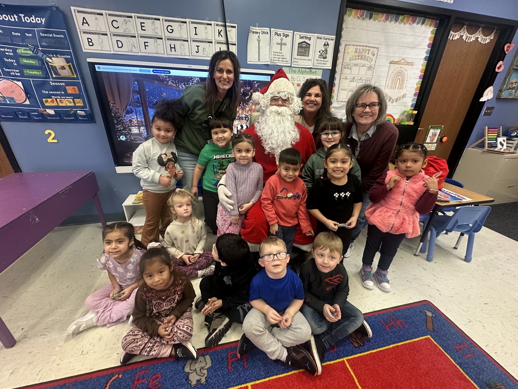 Kids posing with teachers with Santa and preschool classroom