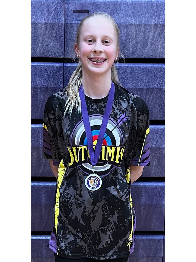 girl with a black and purple and yellow archery jersey with a purple ribbon and white medal around her neck