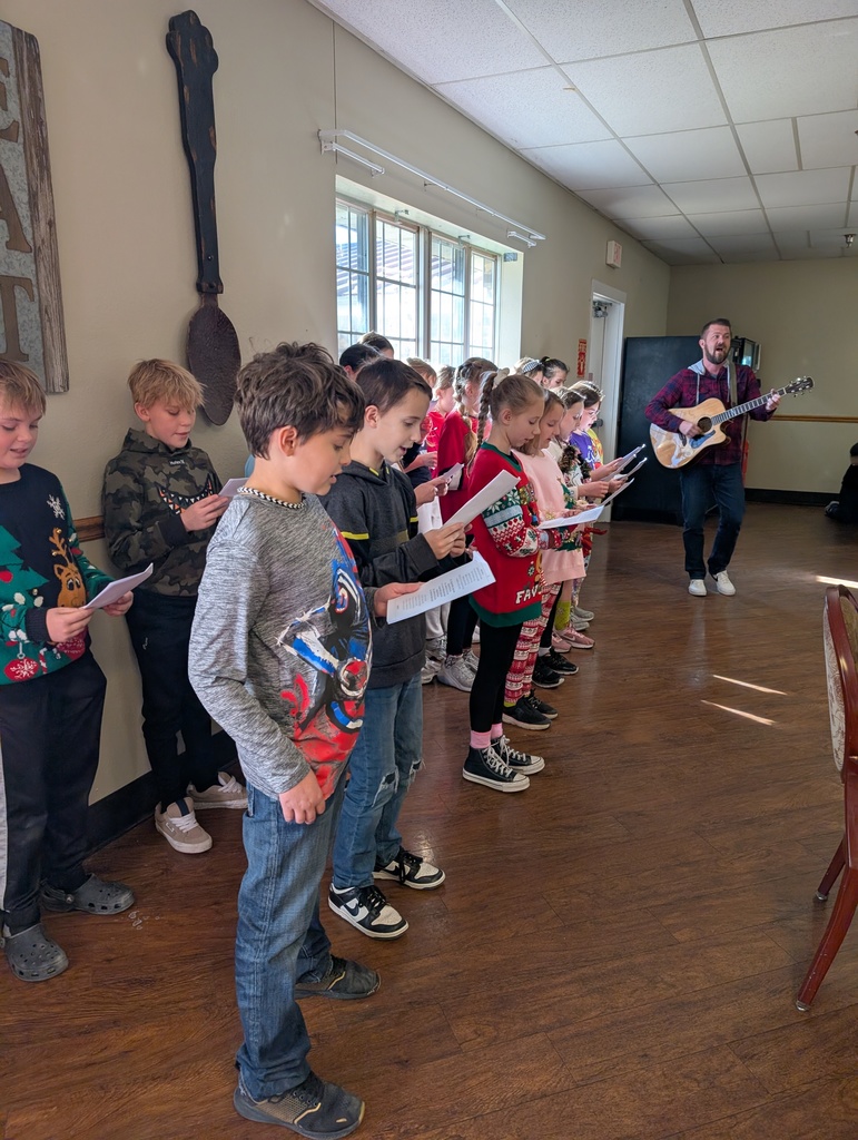 The photo shows the Pacific Intermediate JAG Club and 5th grade choir students spreading holiday cheer at the Pacific Care Center