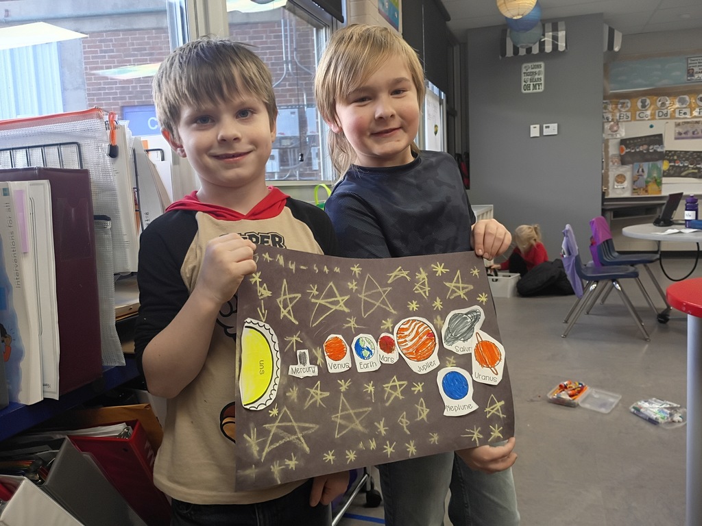 Students smiling with their solar system project. 
