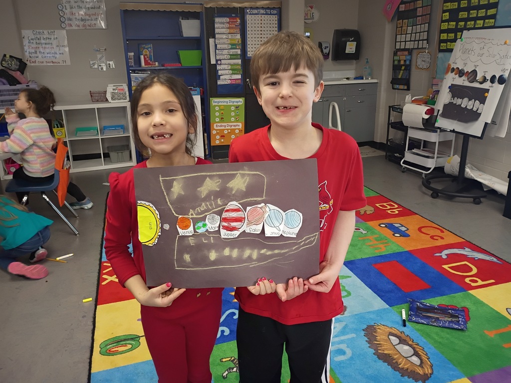 Students smiling with their solar system project. 