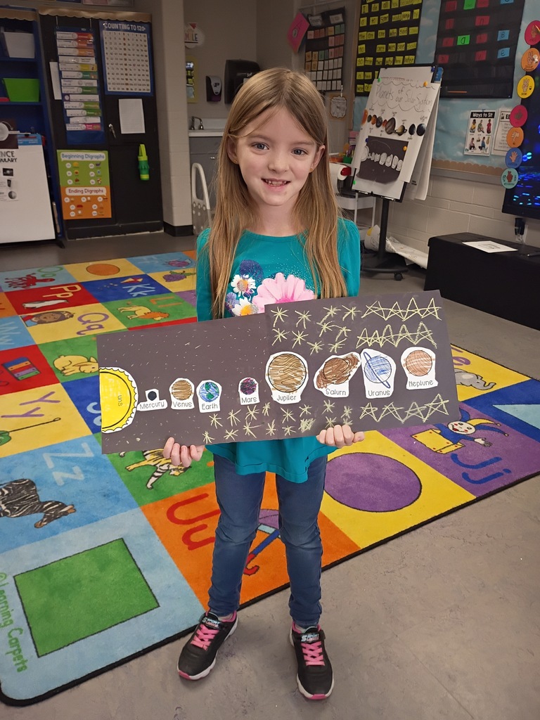 Student smiling with their solar system project. 