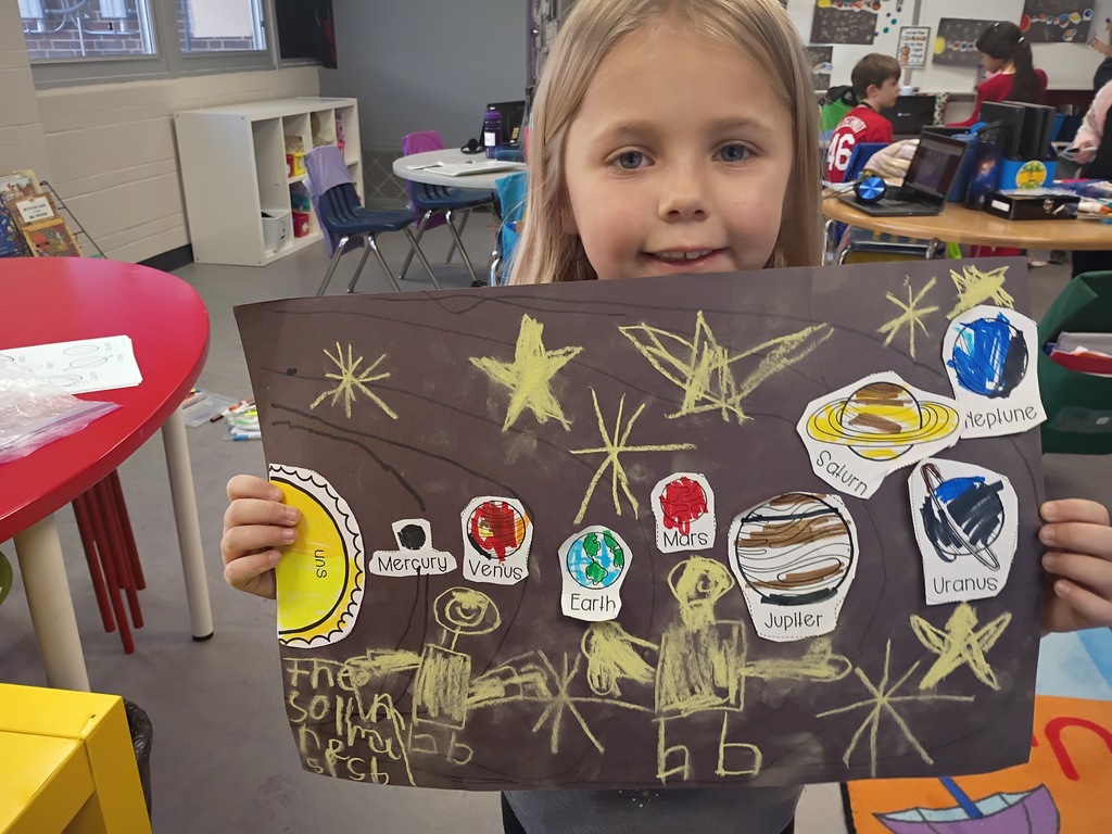 Student smiling with their solar system project. 