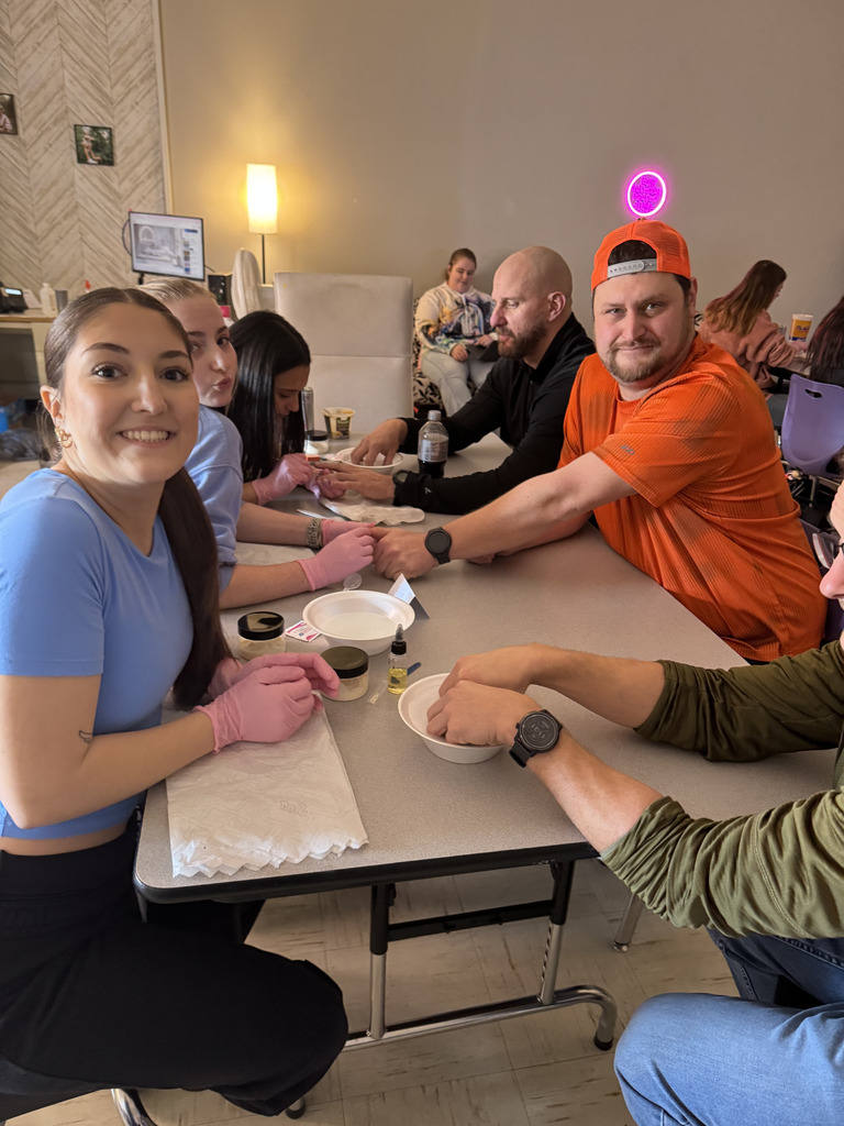 Cosmetology students providing manicures to staff members.