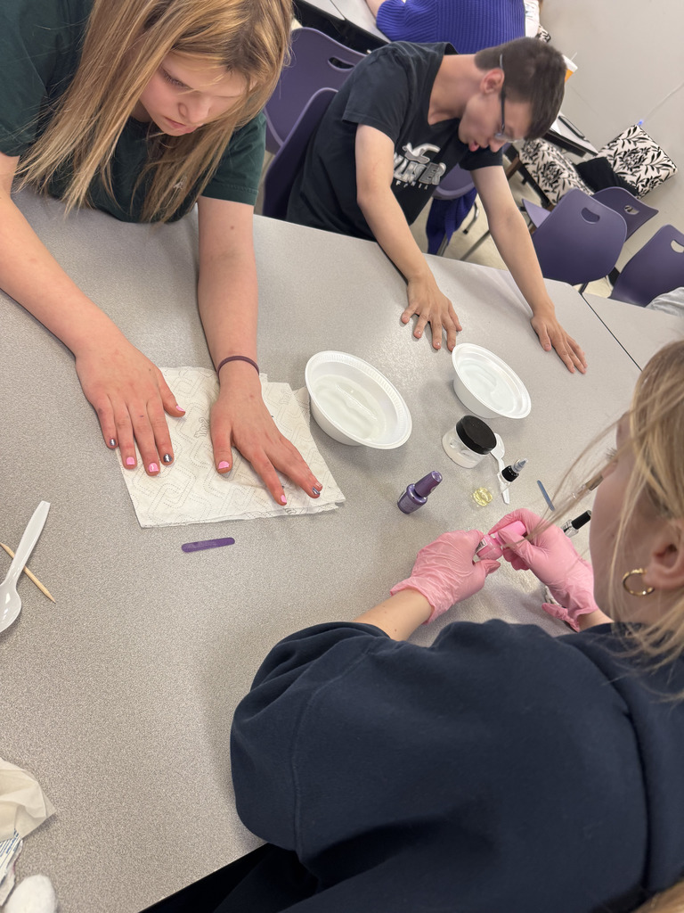 Cosmetology students providing manicures to students.