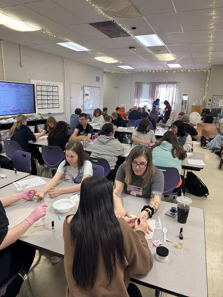 Cosmetology students providing manicures to staff members.