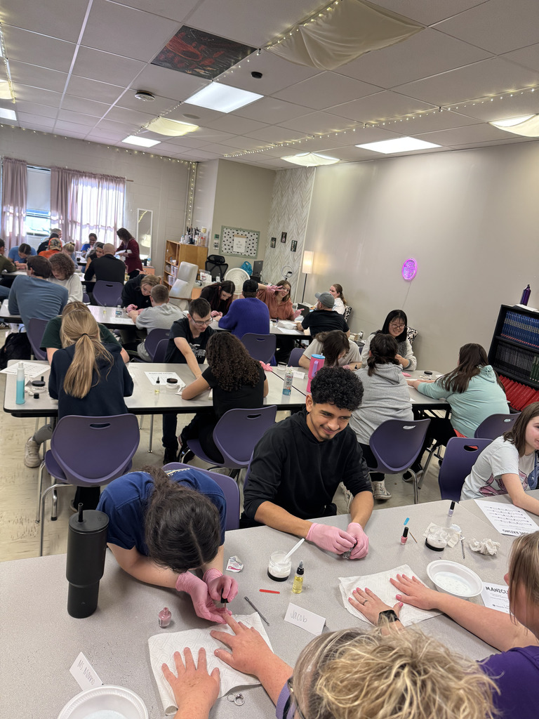 Cosmetology students providing manicures to staff members.