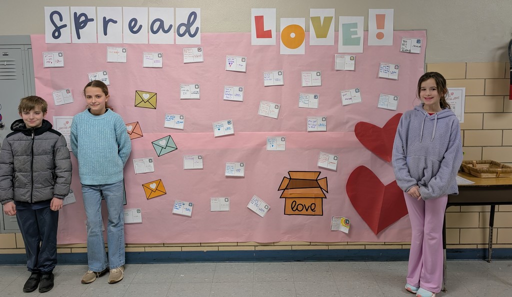 Students standing next to "Spread Love!" wall art.