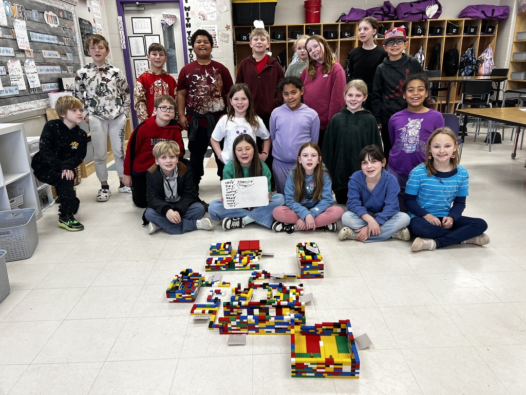 Elementary students posing next to their LEGO build.