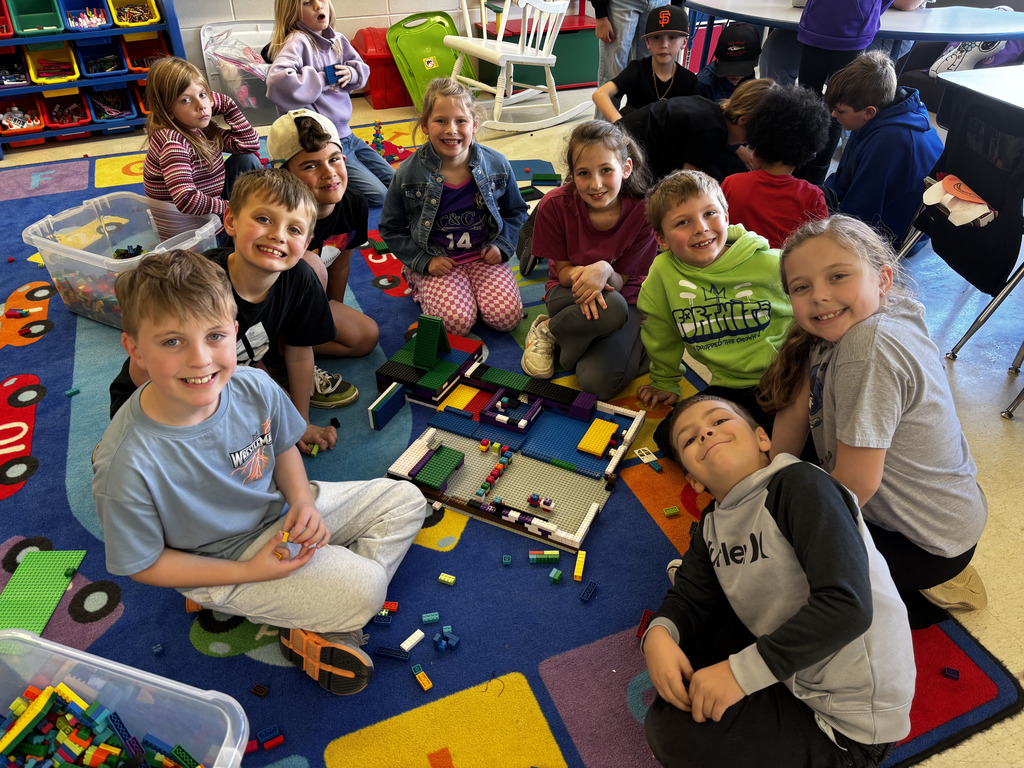 Elementary students posing next to their LEGO build.