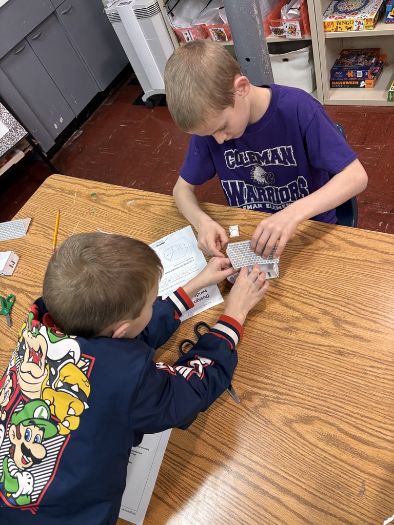 Two young students making a paper house together. 