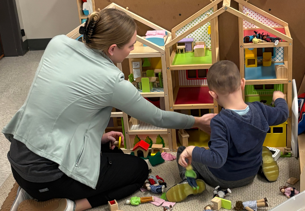 Teacher and student playing with a playhouse.
