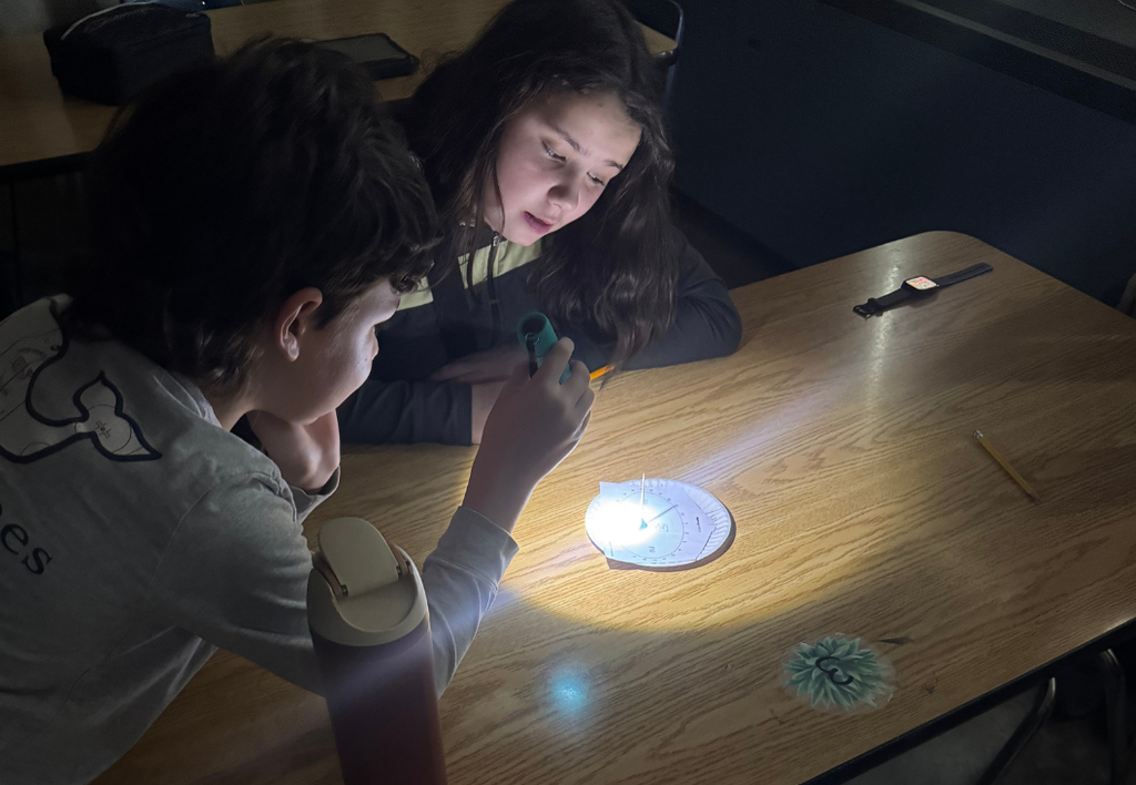 Students exploring an activity about Eath in the dark with a flashlight.