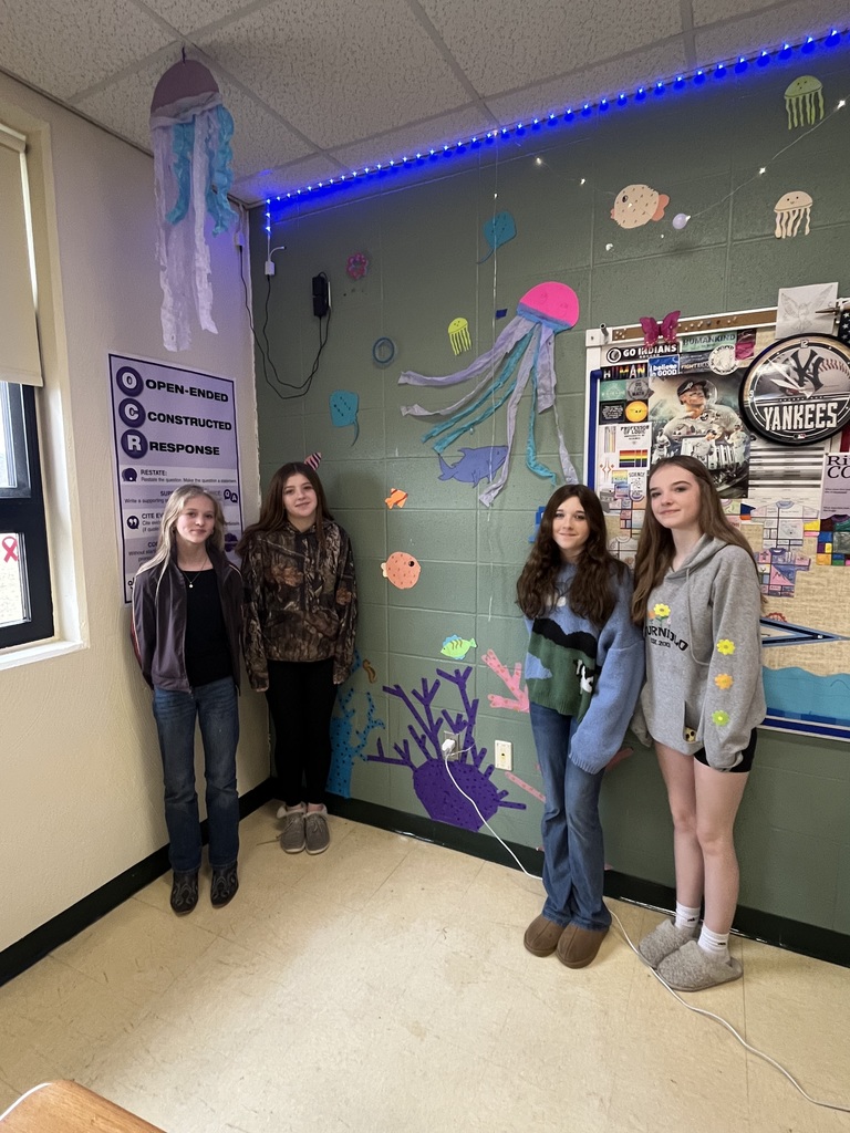 Four students standing next to their ocean themed wall art.