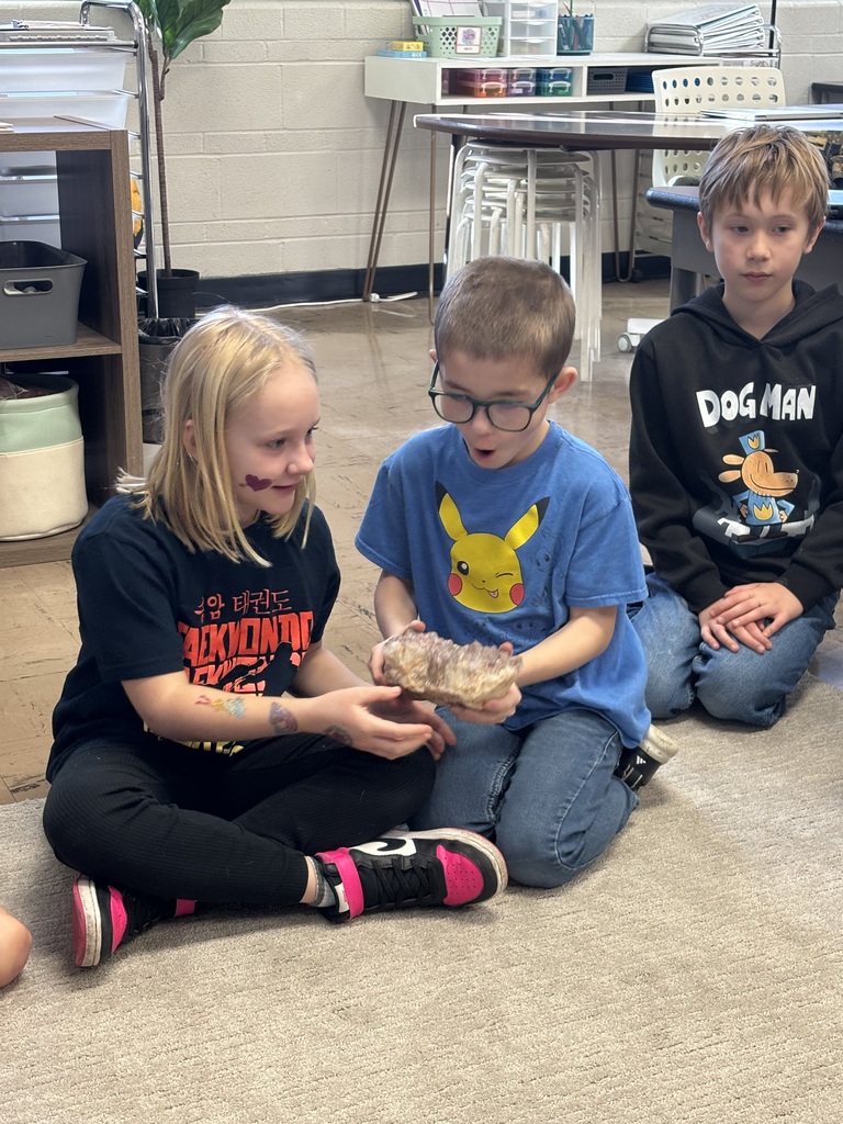 Two students holding a crystal with wow facial expressions.