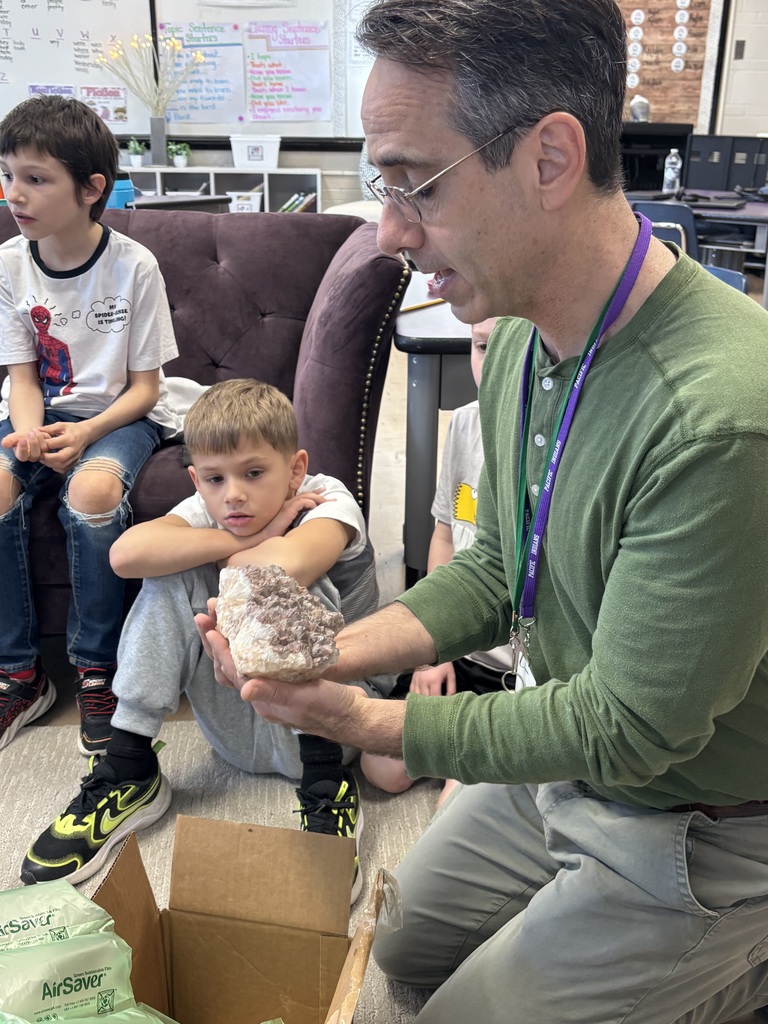Staff member showing his rock collection to a classroom of students.