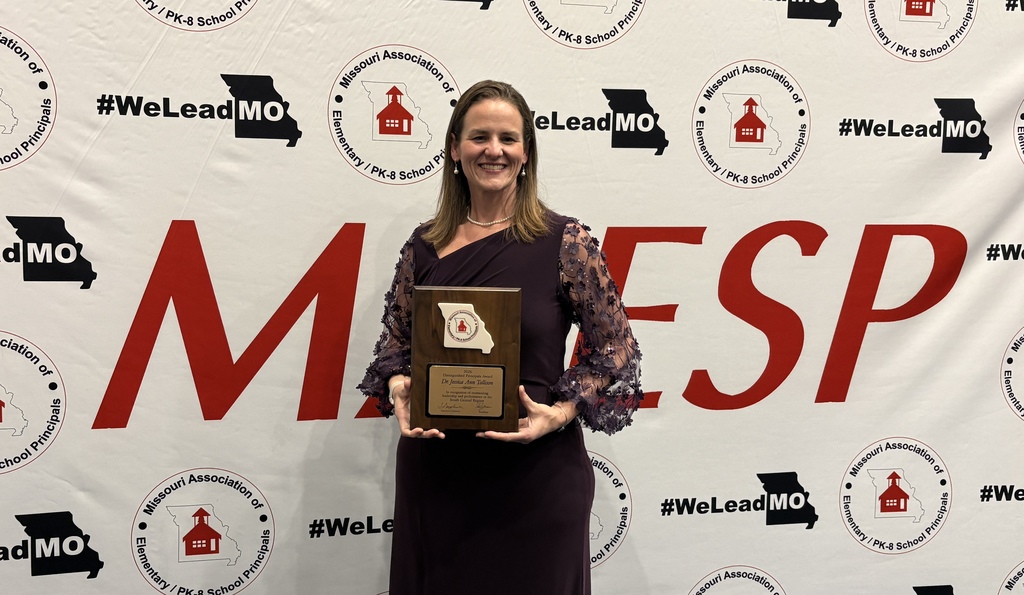 Dr. Jessica Tollison in front of MAESP banner holding recognition.