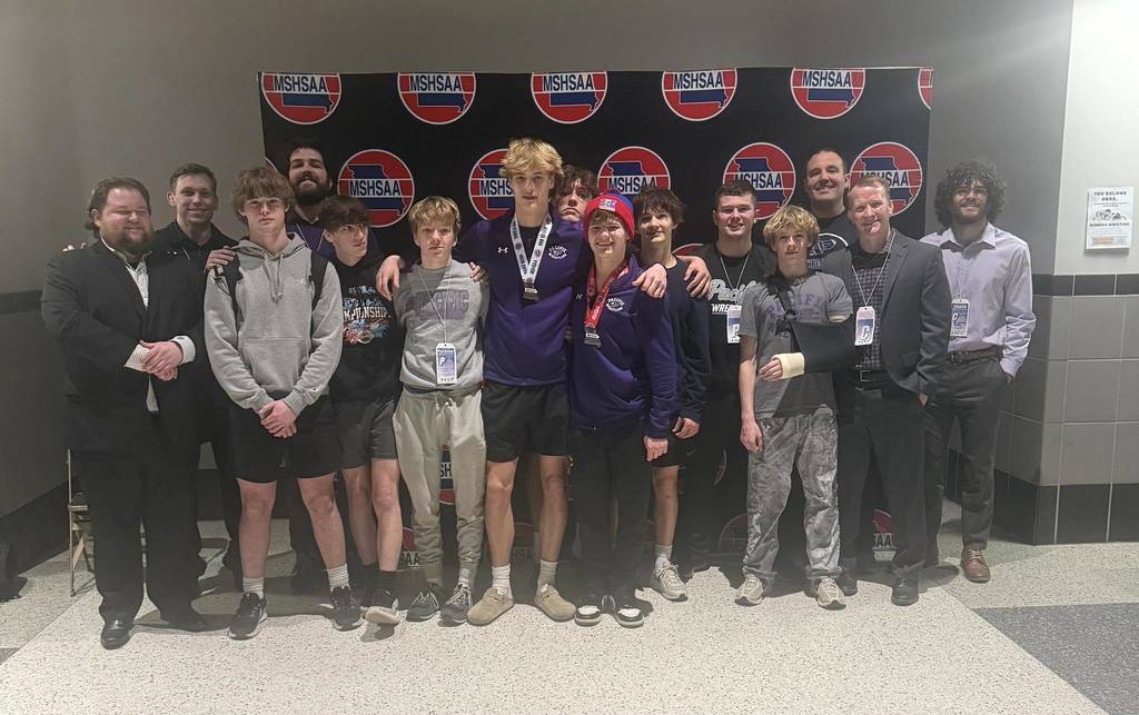 Boys wrestling group photo in front of MSHSAA banner.