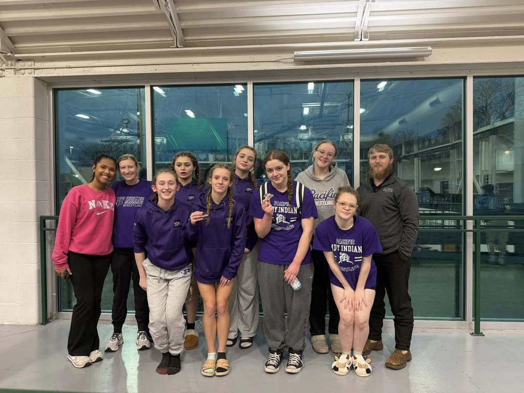 Girls wrestling group photo inside building.