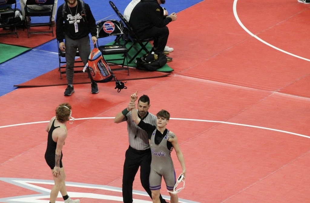 Boys wrestling winning match with arms up.