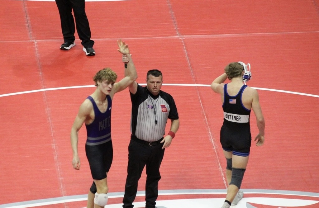 Boys wrestling winning match with arms up.