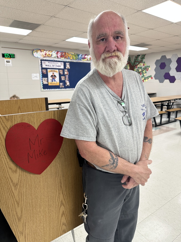 Teacher posing with his heart-shaped paper message from students.