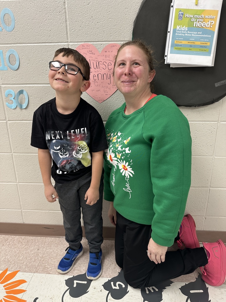 Teacher posing with a student in front of her heart-shaped paper message.