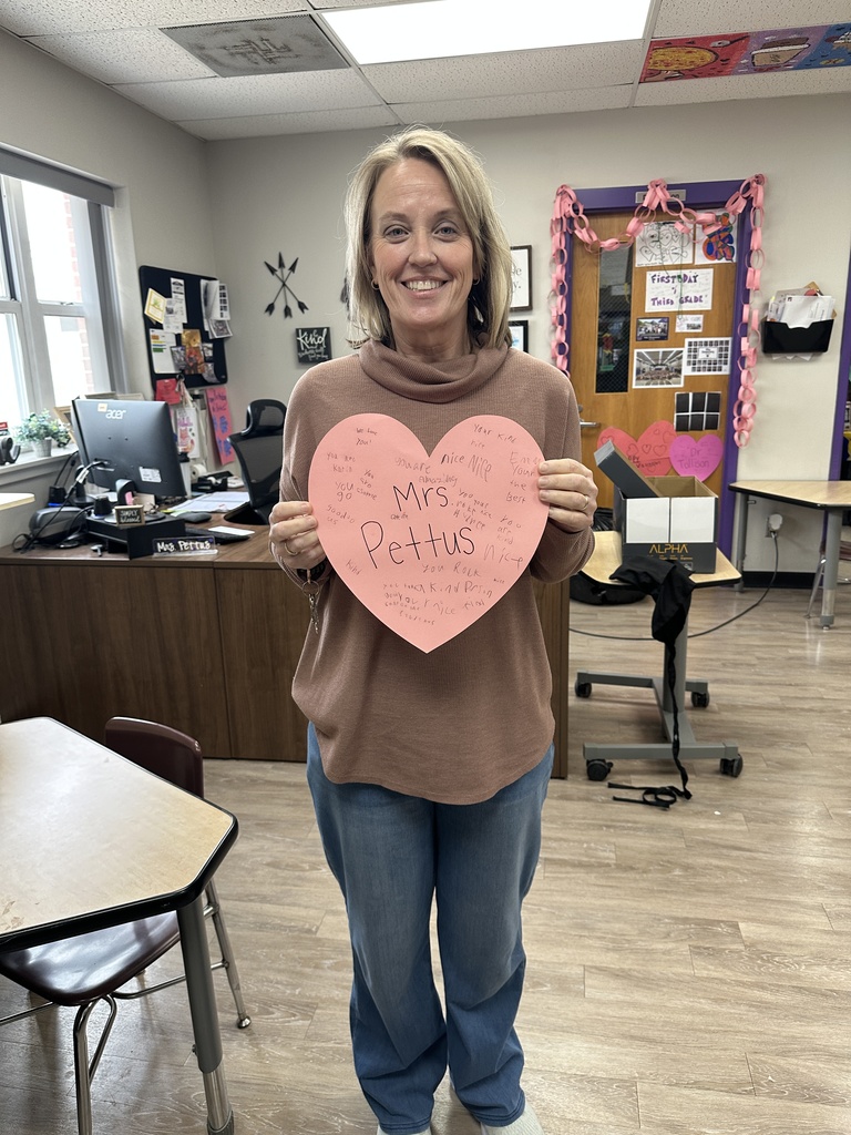 Teacher posing with her heart-shaped paper message from students.