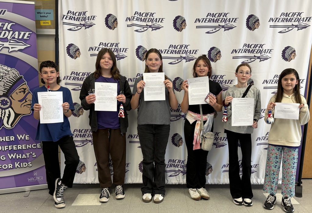 Six students posing for a group photo in front of a Pacific Intermediate banner.