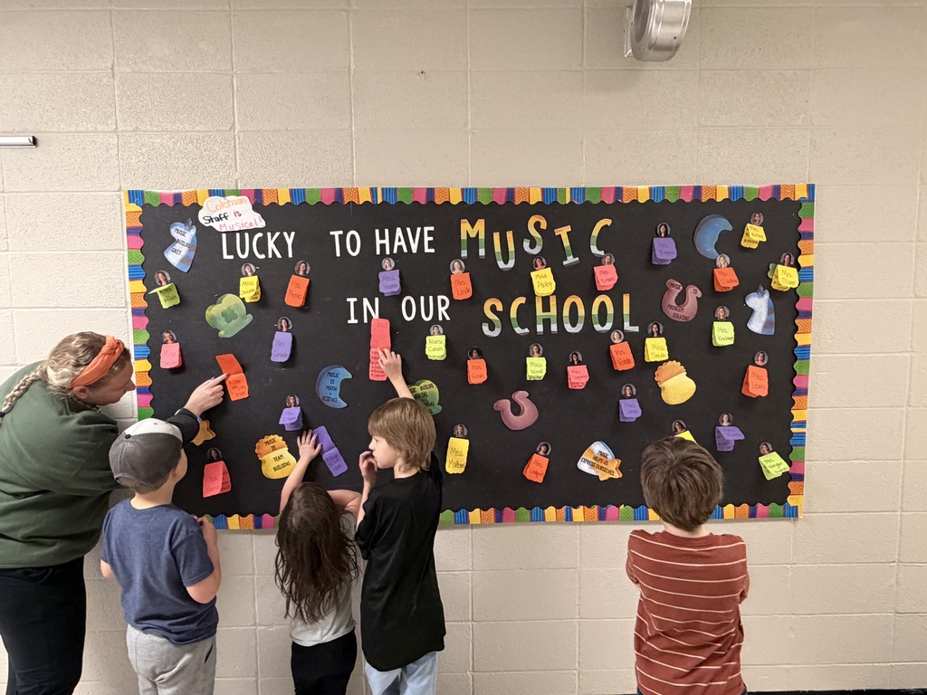 Teacher and four students taping colorful paper pieces to a music themed board.