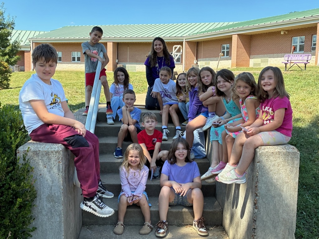 Group of elementary students posing on a staircase outside on a sunny day.