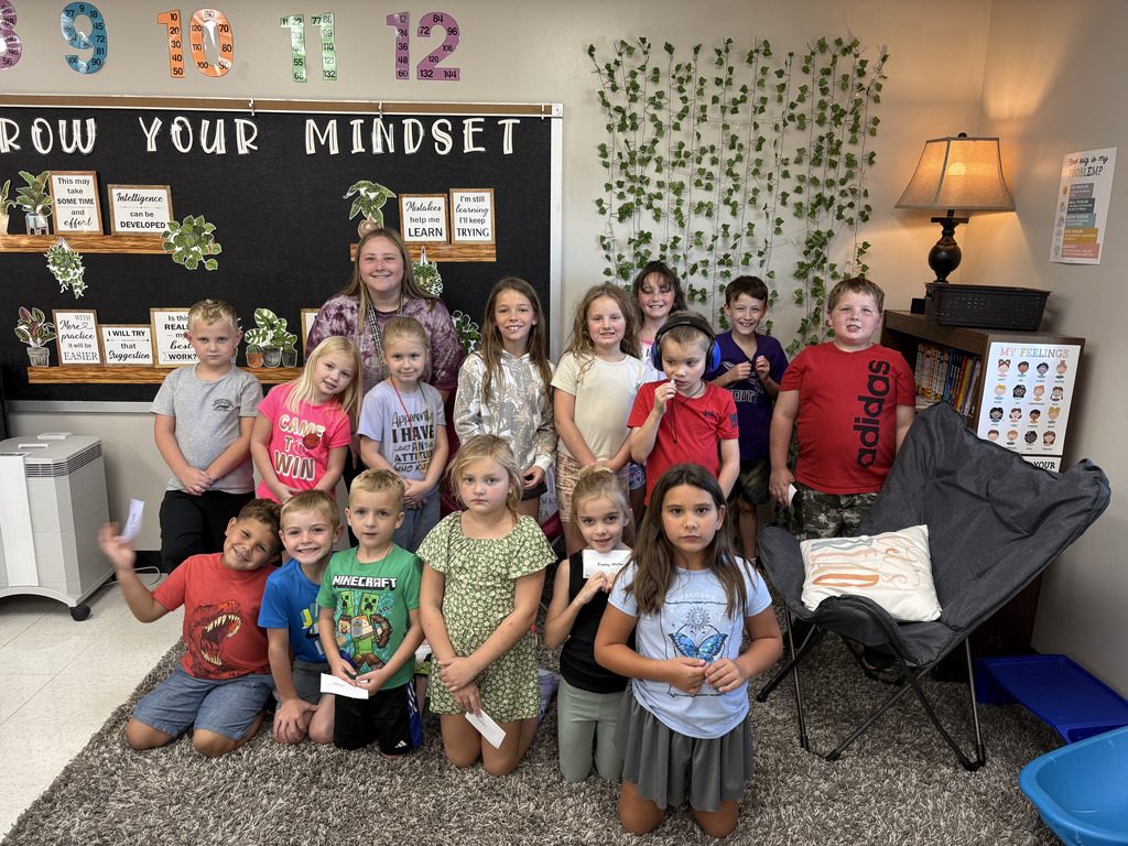 Group of elementary students posing with their teacher in a classroom.