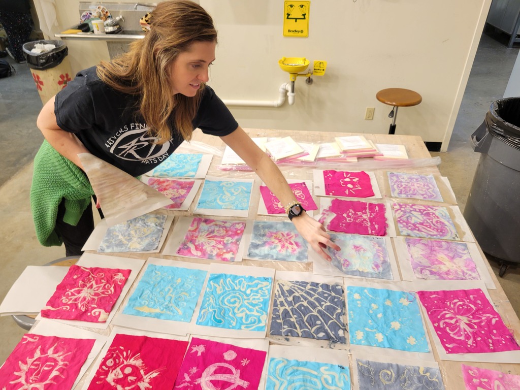 Multiple multicolor water paintings laying out on a table to dry.