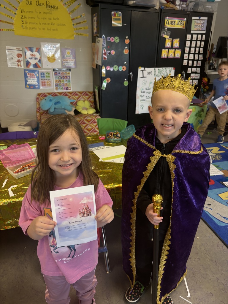 Two students, one dressed as a king, holding paper artwork.