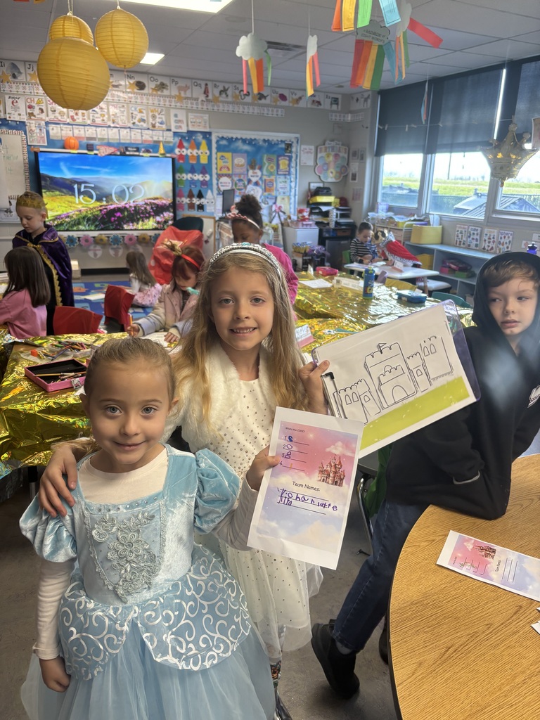 Two students dressed as queens holding paper artwork.