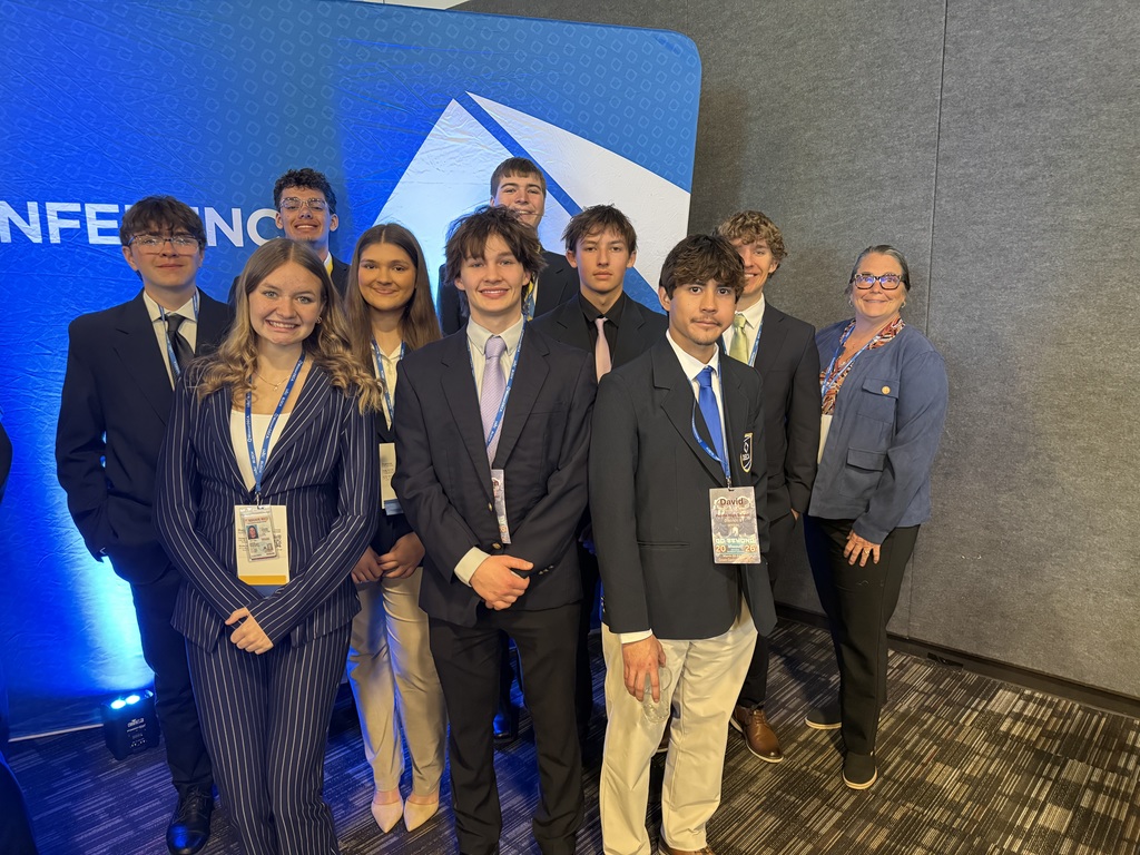 Students and staff member standing for a group photo in front of a blue banner.