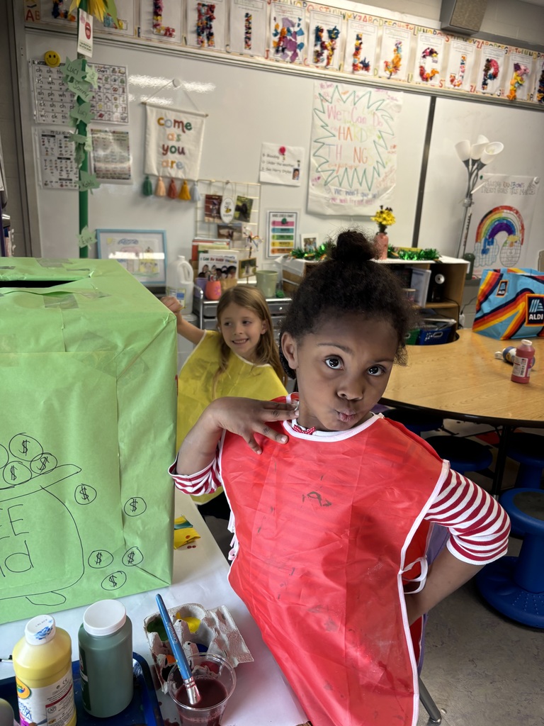 Two students smiling for a photo while working on a painting activity.