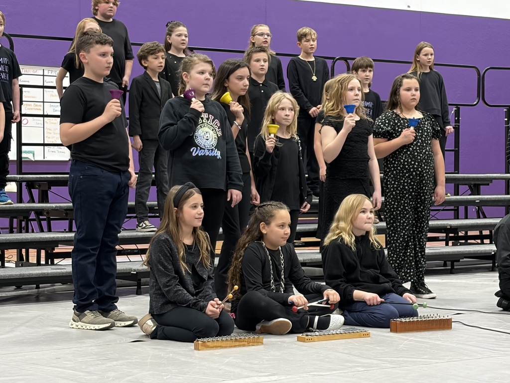 Group of students dressed in black performing music in a gym.