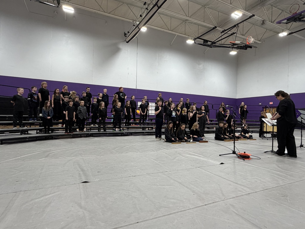 Group of students dressed in black performing music in a gym.