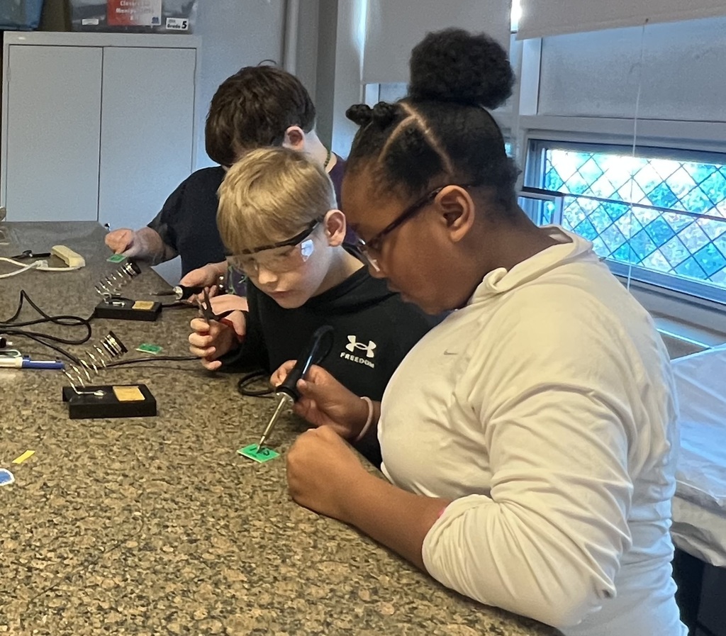 Three students using tools in the classroom.