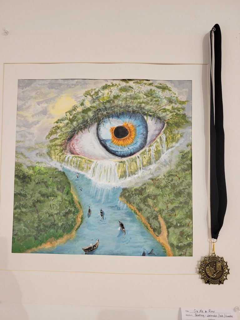 A piece of art showing an eye displaying on a wall with a medal attached to it.
