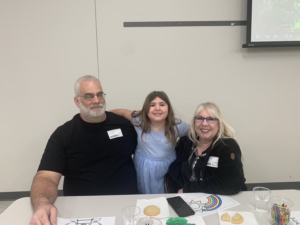 A young student smiling in between two adults.